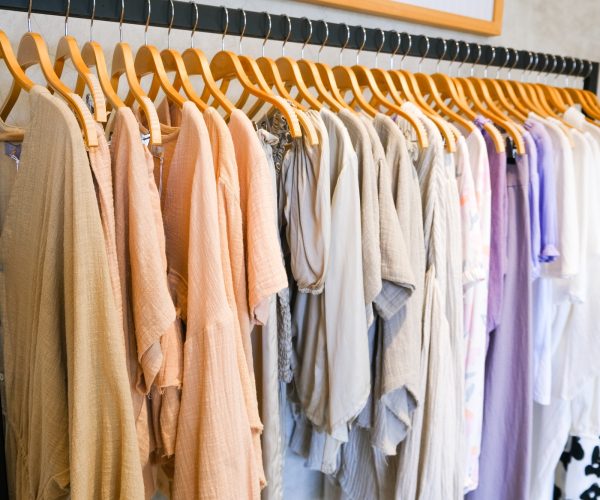 many cloths on hangers in retail fashion shop.